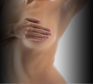 Young and naked woman with one hand raised and the other covering her breasts stock image