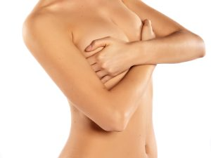 Young and naked woman with one hand raised and the other covering her breasts stock image