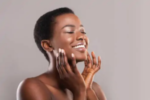Happy black woman with closed eyes touching soft smooth skin stock image
