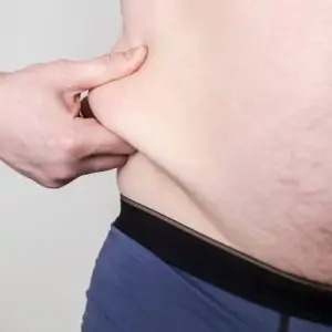 overweight person pinches himself on the fat side stock photo